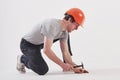 Fixing the floor. Man in casual clothes and orange colored hard hat have some work using hammer. White background Royalty Free Stock Photo