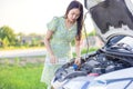 Fixing Her Broken Down Car, a young woman pours a water for washing glasses into her car