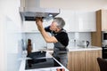Fixing your technology problem. Aged repairman in uniform working, fixing broken kitchen extractor fan using screwdriver Royalty Free Stock Photo
