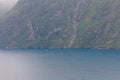 Fjord landscape with sail boat sailing glittering waters, in background lone house on rocky cliff, shot under bright summer light Royalty Free Stock Photo