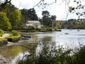 Fjord at low tide, with forest and a house on the shore, sailing boats moored at buoys in the blurred background, branches and bu