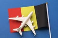 Flag of Belgium and a toy plane on a blue background, concept on the theme of travel to Belgium, top view