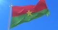 Flag of Burkina Faso waving at wind in slow with blue sky, loop