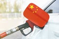 Flag of China on the car`s fuel filler flap with gas pump nozzle in the tank Royalty Free Stock Photo