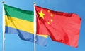 Flag of China and Republic of Gabon on cloudy sky. Royalty Free Stock Photo