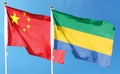 Flag of China and Republic of Gabon on cloudy sky. Royalty Free Stock Photo