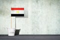 Flag of Egypt, on a stick, in a small bucket, against the background of a concrete wall. Copy space. Signs and Symbols.