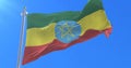 Flag of Ethiopia waving at wind with blue sky in slow, loop