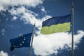 Flag of Europe and Ukraine on flagpoles against the blue sky Royalty Free Stock Photo
