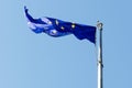 Flag of the European Union on the flagpole against the blue sky.