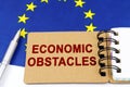 On the flag of the European Union lies a pen and a notepad with the inscription - economic obstacles Royalty Free Stock Photo