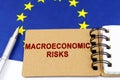 On the flag of the European Union lies a pen and a notepad with the inscription - macroeconomic risks