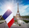 Flag of France is on background of the Eiffel Tower, blue sky, clouds and sun. Paris. French flag is a tricolour flag. Royalty Free Stock Photo