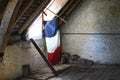 Flag of France bathed in light suspended in an old attic house.