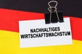 On the flag of Germany lies a business card with the inscription - sustainable economic growth