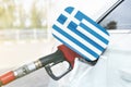 Flag of Greece on the car`s fuel filler flap with gas pump nozzle in the tank Royalty Free Stock Photo