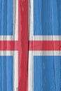 The flag of Iceland on a dry wooden surface, cracked with age. Light pale faded paint. Patriotic background or wallpaper.