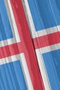 The flag of Iceland on a dry wooden surface, cracked with age. Light pale faded paint. Patriotic background or wallpaper.