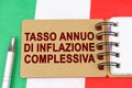 On the flag of Italy lies a pen and a notebook with the inscription - Annual headline inflation rate