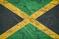 Flag of Jamaica on stone wall, grunge background. Flag of Jamaica depicted in bright paint colors