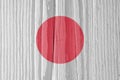 The flag of Japan on a dry wooden surface, cracked with age. Light pale faded paint. Patriotic background or wallpaper. Hinomaru,