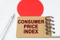 On the flag of Japan lies a pen and a notebook with the inscription - consumer price index