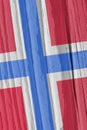 The flag of Norway on a dry wooden surface, cracked with age. Light pale faded paint. Patriotic background or wallpaper.