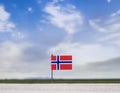 Flag of Norway with vast meadow and blue sky behind it. Royalty Free Stock Photo