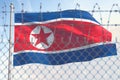 Flag of Nothern Korea behind barbed wire fence. Concept of sanctions, embargo, dictatorship, discrimination and violation of human