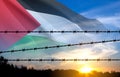 Flag of Palestine with barbed wire against the sunset