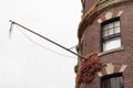 Flag pole extending from the face of a brick brownstone building with ivy on face Royalty Free Stock Photo