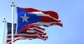 Flag of Puerto Rico waving in the wind with the United States flag on a clear day Royalty Free Stock Photo