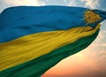 Flag of Rwanda waving in the wind with sunset sky background, close-up