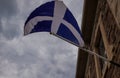 The flag of Scotland hangs on the flagpole of an old building against the background of a cloudy sky Royalty Free Stock Photo