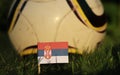 Flag of Serbia between stems of grass and in the background wonderfull classic ball. World Championship 2022. Euro 2020. Serbian