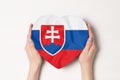 Vlajka Slovenska na krabici v tvare srdca v ženských rukách. Biele pozadie