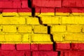 Flag of Spain on the brick wall with big crack in the middle. Destruction and separatism concept