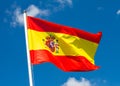 Flag of Spain waving in the wind on flagpole against the sky with clouds on sunny day Royalty Free Stock Photo