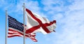 The flag of the state of Alabama waving alongside the national flag of the United States on a sunny day