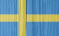 The flag of Sweden on a dry wooden surface, cracked with age. Light pale faded paint. Patriotic background or wallpaper.