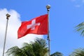 Flag of Switzerland against coconut palm and blue sky background ar Fernando de Noronha, Brazil. Travel concept Royalty Free Stock Photo