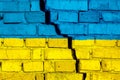 Flag of Ukraine on the brick wall with big crack in the middle. Destruction and separatism concept