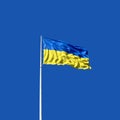 Flag of Ukraine on a flagpole filled with wind against a blue sky Royalty Free Stock Photo