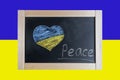 Flag of Ukraine and a heart drawn in chalk. Children write the text Peace on the blackboard with chalk Royalty Free Stock Photo
