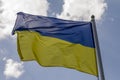 Flag of Ukraine waving in the wind on flagpole against the sky with clouds on sunny day Royalty Free Stock Photo