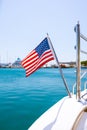 The flag of the United States flutters in the wind on a stainless steel flagpole at the stern of a motor yacht. Marina in the port Royalty Free Stock Photo