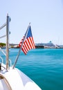 The flag of the United States flutters in the wind on a stainless steel flagpole at the stern of a motor yacht. Marina in the port Royalty Free Stock Photo