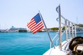 The flag of the United States flutters in the wind on a stainless steel flagpole at the stern of a motor yacht. Marina in the port Royalty Free Stock Photo