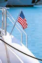 The flag of the United States flutters in the wind on a stainless steel flagpole at the stern of a motor yacht. Marina in the port Royalty Free Stock Photo