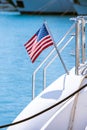 The flag of the United States flutters in the wind on a stainless steel flagpole at the stern of a motor yacht. Marina in the port Royalty Free Stock Photo